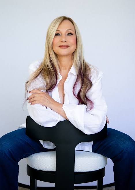 Rhonda Shear seated in a white blouse